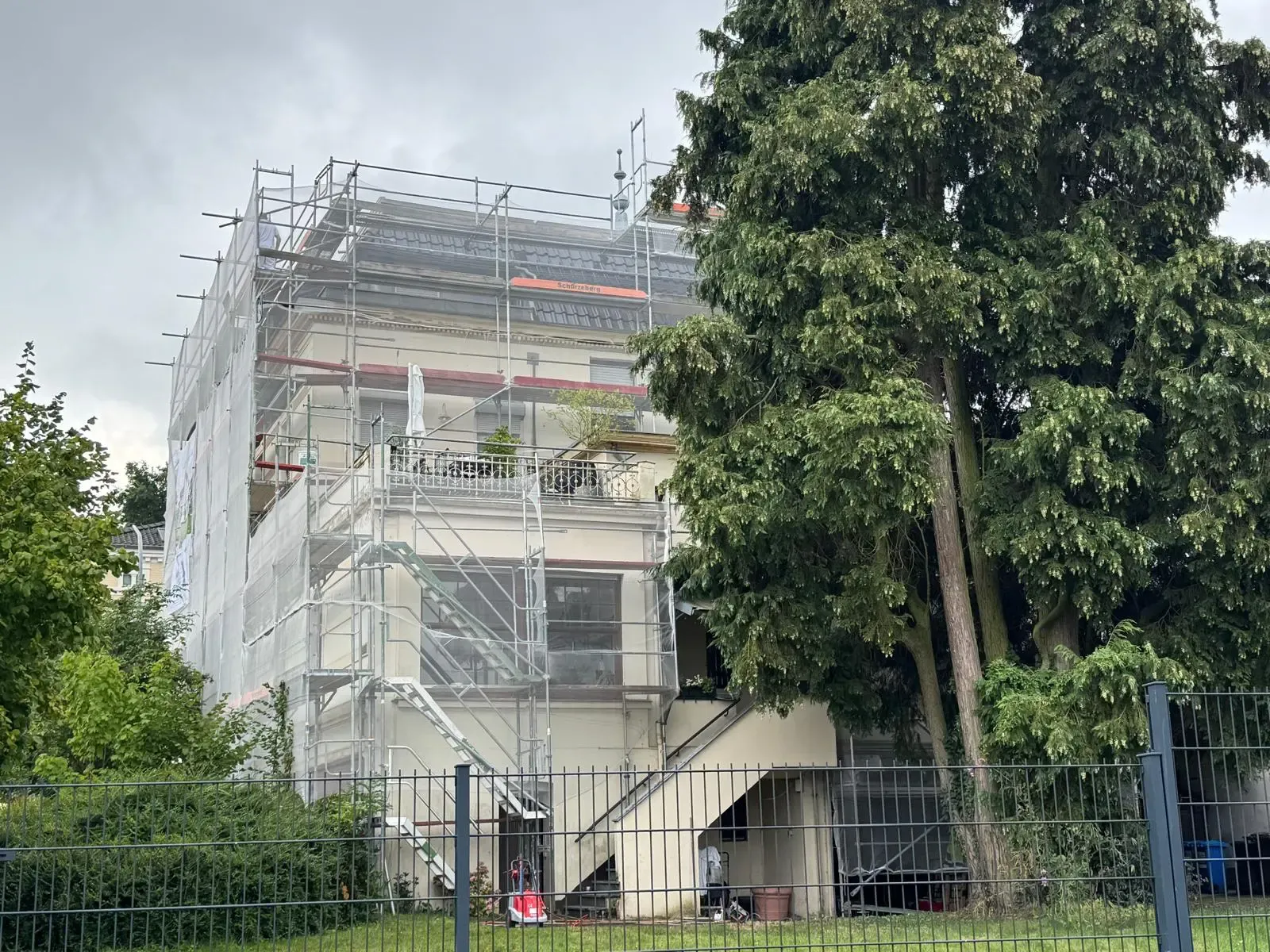 Fassadensanierung eines Wohnhauses in Korschenbroich durch farbDESIGN & WERKstatt – Malerbetrieb bei Außenarbeiten mit Gerüst und Schutzplane.