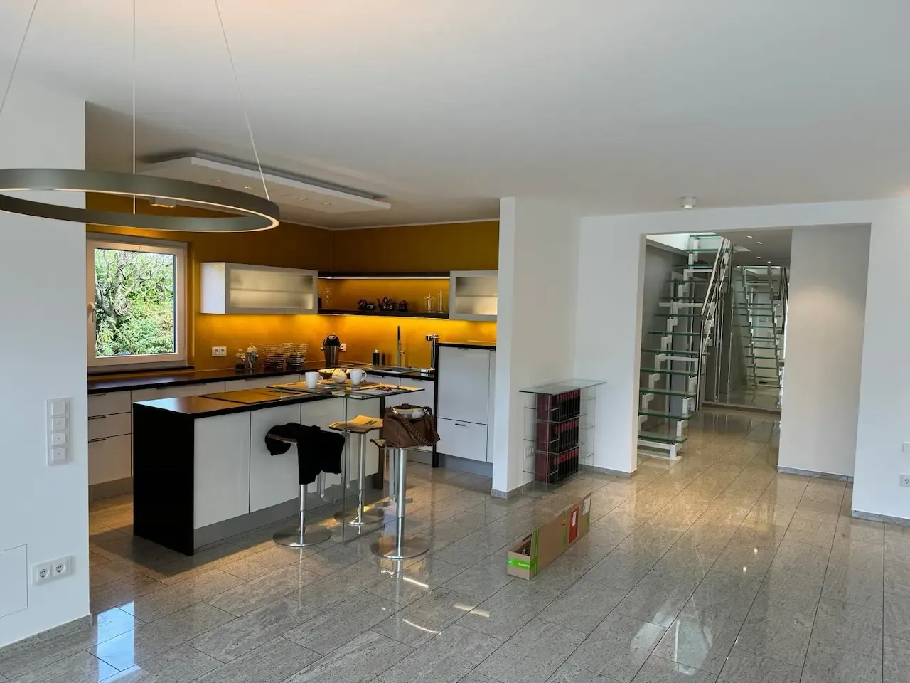 Weitläufige Wohnküche mit goldenen Wänden und minimalistischem Design: Eine elegante, modern gestaltete Küche mit goldenen Wänden und klaren Linien, die dem Raum Wärme und Exklusivität verleiht. Die Renovierung wurde von farbDESIGN und WERKstatt ausgeführt.