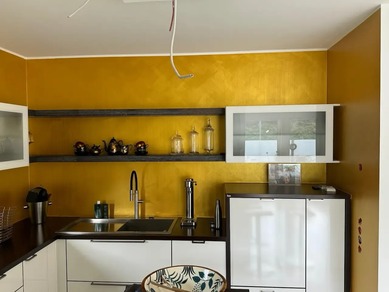 Moderne Küche mit goldenen Wänden und Glasakzenten: Eine moderne Küche mit strahlend goldener Wand und eleganten Glasakzenten, umgesetzt von farbDESIGN und WERKstatt. Die Vergoldung verleiht dem Raum eine edle Note.