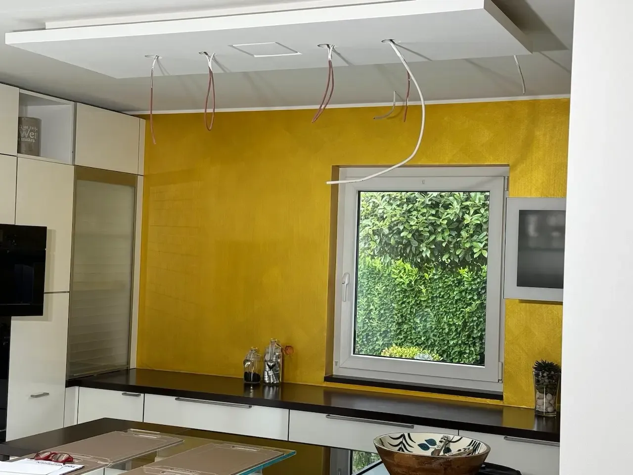 Küchenbereich mit goldener Wand und minimalistischer Einrichtung: Der Küchenbereich mit einer warmen, goldfarbenen Wand und minimalistischen Design-Elementen, die einen luxuriösen und modernen Wohnstil unterstreichen, von farbDESIGN und WERKstatt renoviert.