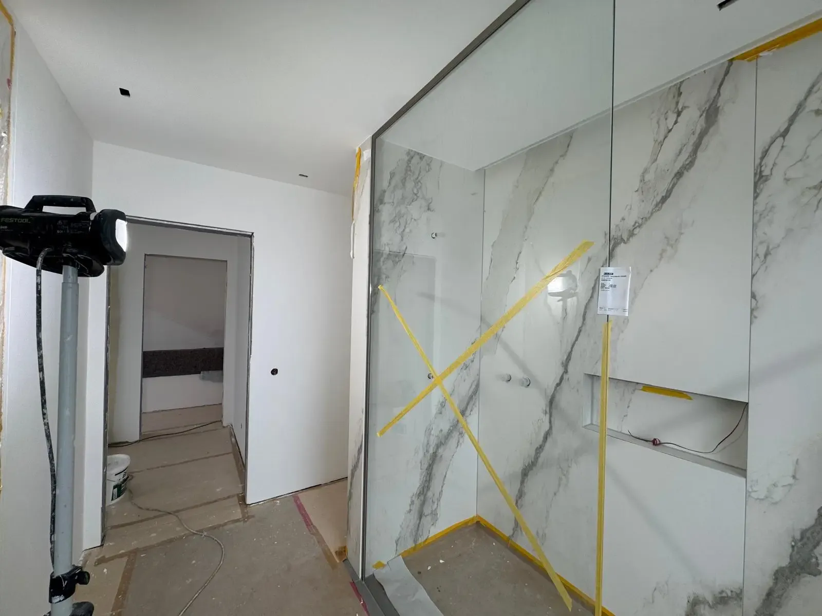 Modernes Neubau-Badezimmer mit großflächigen Marmoroptik-Fliesen und einer edlen Glasdusche.