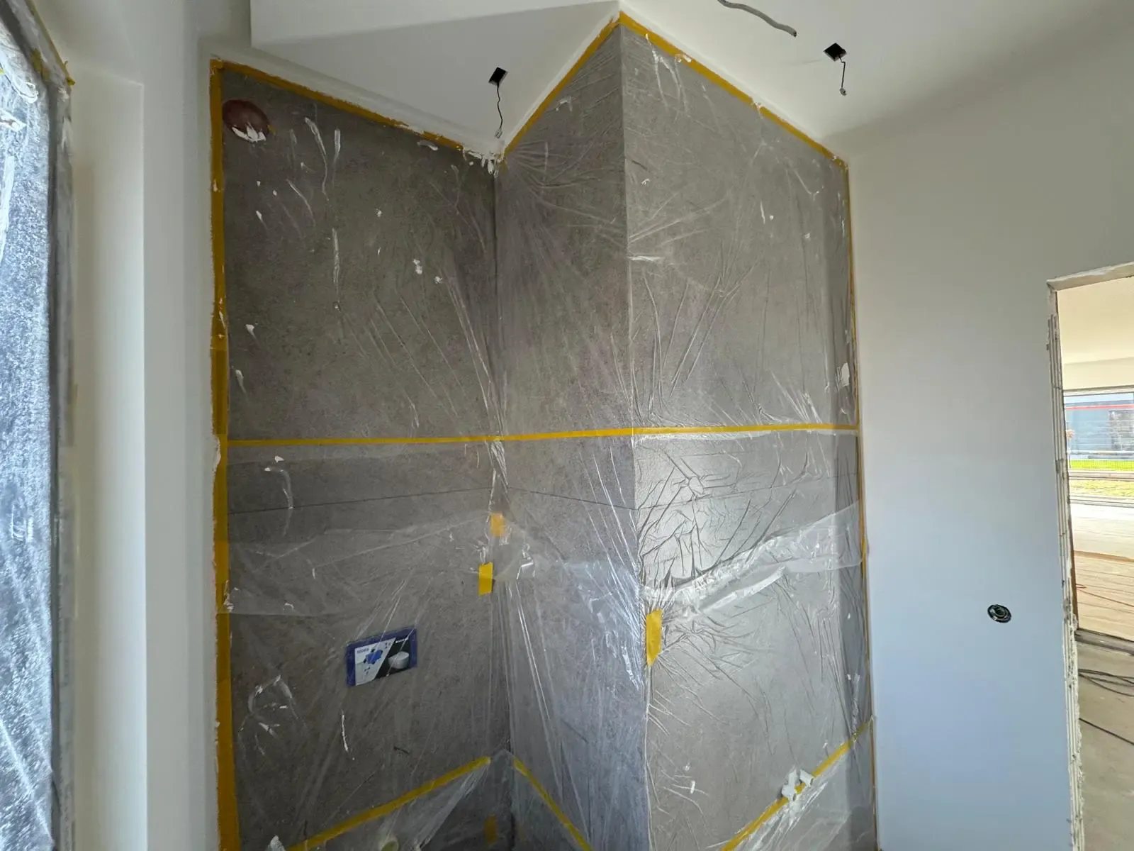 Wandbereiche mit Schutzfolie abgedeckt, vorbereitet für die Fliesenmontage in einem Neubau.