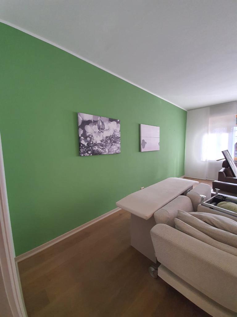 Frisch renovierter Behandlungsraum in einer Praxis mit lebendiger grüner Wandfarbe und moderner Einrichtung.